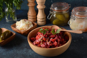 Vinegret or vinaigrette. Traditional Russian red salad with cooked and pickled vegetables, peas, beetroot, in wooden bowl on rustic background.
 Vegan healthy dietary food