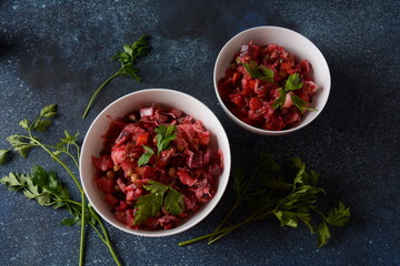 Vinegret or vinaigrette. Traditional Russian red salad with cooked and pickled vegetables, peas, beetroot, in white bowl on grey background.
 Vegan healthy dietary food