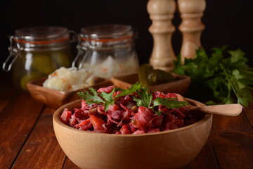 Vinegret or vinaigrette. Traditional Russian red salad with cooked and pickled vegetables, peas, beetroot, in wooden bowl on rustic background.
 Vegan healthy dietary food