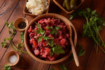 Vinegret or vinaigrette. Traditional Russian red salad with cooked and pickled vegetables, peas, beetroot, in wooden bowl on rustic background.
 Vegan healthy dietary food