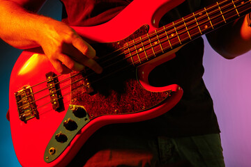 Close up. Young inspired and expressive musician, guitarist performing on gradient colored background in neon light. Concept of music, hobby, festival, art. Joyful artist, colorful, bright portrait.