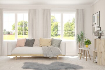 Fototapeta premium White living room with sofa and summer landscape in window. Scandinavian interior design. 3D illustration