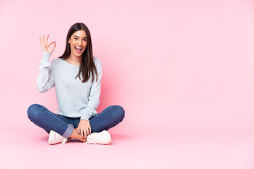 Young caucasian woman isolated on pink background surprised and showing ok sign