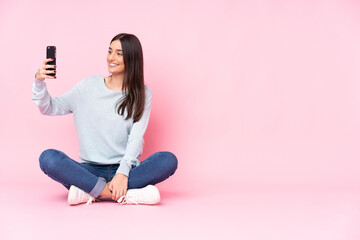 Young caucasian woman isolated on pink background making a selfie