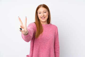 Young redhead woman with pink sweater over isolated white background smiling and showing victory sign