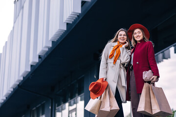 two beautiful fashion models walking outside with shopping bags