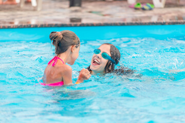 Fototapeta na wymiar Two cute little sisters girls swim in the pool during vacation on a sunny warm summer day. The concept of the long-awaited vacation. Advertising space