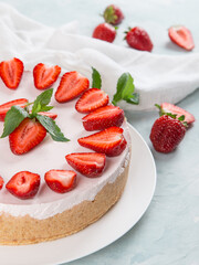 Sweet breakfast, delicious cheesecake with fresh strawberries and mint, homemade recipe without baking, on a blue stone table. Copy space.