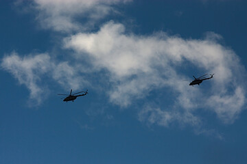 two helicopters in a cloudy summer sky