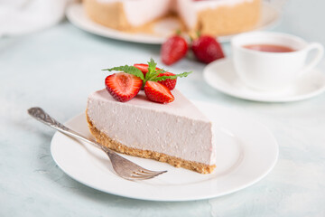 Sweet breakfast, tea and delicious cheesecake with fresh strawberries and mint, homemade recipe without baking, on a blue stone table. Copy space.