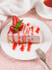 Sweet breakfast, tea and delicious cheesecake with fresh strawberries and mint, homemade recipe without baking, on a pink stone table. Copy space.