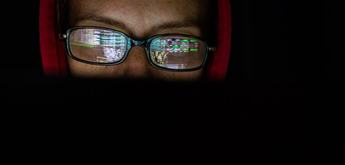hacker at computer data reflecting in eyeglasses