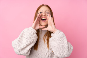 Young redhead woman over isolated pink background shouting and announcing something