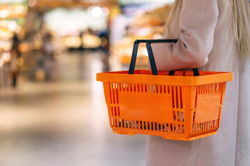 Woman hold orange basket in supermarket.