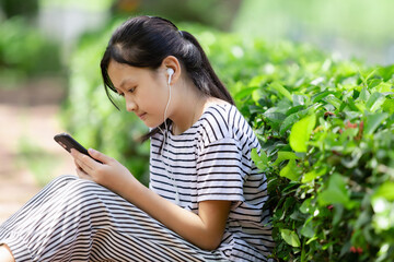 Enjoy sound music. Happy girl listening to music relax in the park after school.