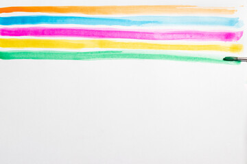 Brush making colorful lines with watercolors on a white background, copy space