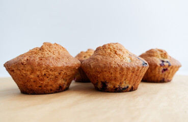 Freshly baked cupcakes muffins on a light brown crafted parchment. Home-made pastries as cooking or baking concept.