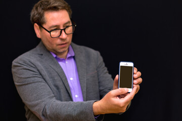 Middle age 40s business man showing smartphone screen over black background