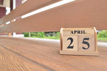 April 25, Number cube with wooden balcony background.