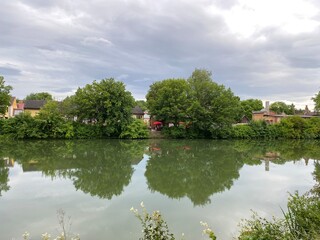 Fototapeta premium Neckar in Rottenburg im Sommer, bei bewegten Himmel. Biergarten, Bäume, Haus, auf der anderen Uferseite