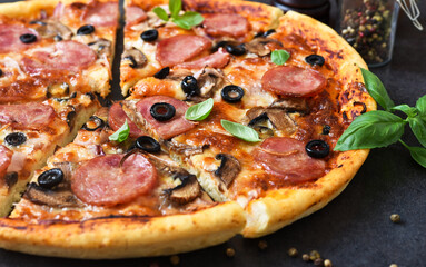 Pizza slices with mushrooms and olives on a black background.
