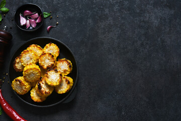 Baked hot corn with butter in a cast-iron pan on a black background. View from above.