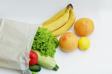 on the table there is a paper bag from which fruits and vegetables are spilled