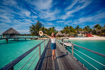 beautiful blonde girl  posing on dock, tropical resort in background