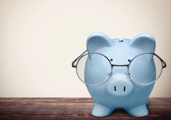 Blue piggy bank in glasses on the desk