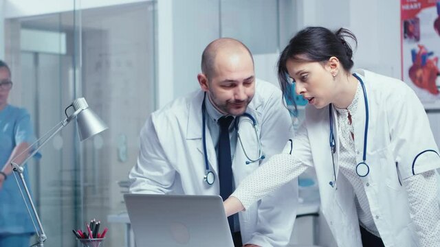 Two doctor colleagues disagreeing over a medical problem while looking at laptop and talking about it. Healthcare system, private modern medical hospital clinic