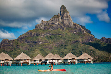 Woman paddling a kayak by the tropical beach.