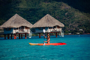 Fototapeta na wymiar Woman paddling a kayak by the tropical beach.