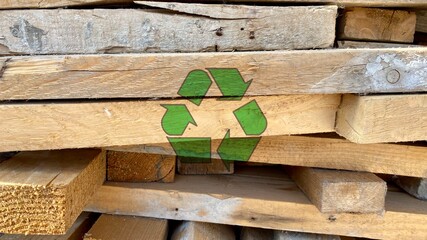 Recycling arrow icon on waste wooden piles from a construction site, reuse and reduce to protect...