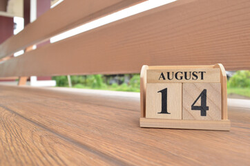 August 14, Number cube with wooden balcony background.