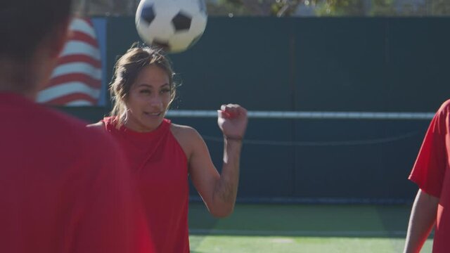 Player heading ball as female soccer team warm up during training before match - shot in slow motion