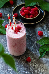 Summer cool milkshake. Raspberry protein shake in glass on a dark background. Copy space.