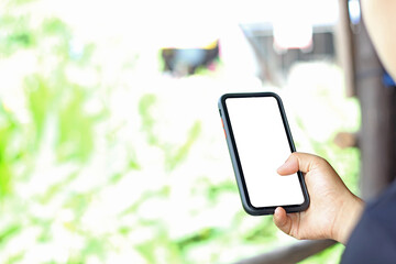 Cropped shot view of woman's hands holding smart phone with blank copy space screen for your text message or information content. Female’s hand holding smart phone with green blur background.