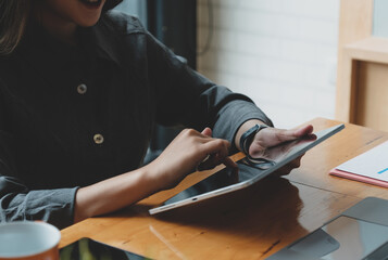 Young pretty asian woman enjoying tablet in co-working space