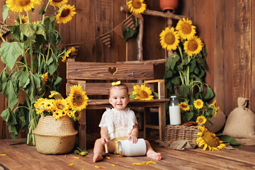 happy little girl having fun and playing among blooming sunflowers near the bench. The child eats cookies with milk