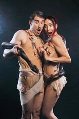 Fototapeta premium Beautiful man and woman Adam and Eve, posing with nature snake on a black background