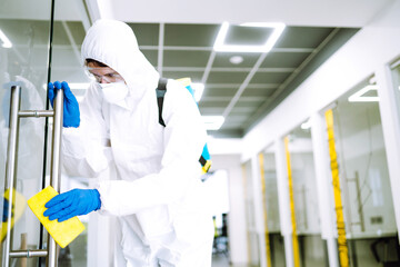 Man in a protective suit washes an office to prevent COVID-19. Cleaning and disinfection office furniture.