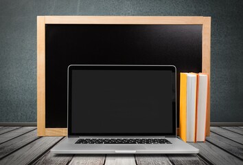 Blackboard with wooden frame and open laptop on the desk