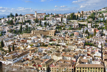 Fototapeta na wymiar Panoramic view of the old part of Granada, Andalusia, Spain. White cozy houses and narrow streets on the hill against the blue sky