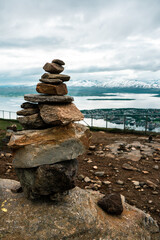 Pile of stones on the hill with view to the Tromso area, northern Norway. Fiord with mountains and sea in the background. Climbing mountain.