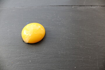 an egg yolk or half of an apricot peach on a grey stone black background there is a place to insert...