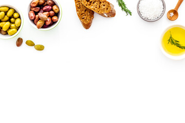 Top view of olives, olive oil, bread on white table top view copy space