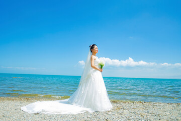 A girl in a wedding dress is modeling by the seaside lake.