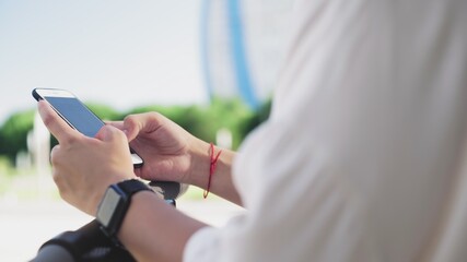 Obraz premium CLose up of female hands is using smartphone after ride on electric kick scooter