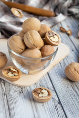 closed and split walnuts in dishes on a light wooden background, textiles, cutting Board