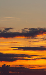 The sky at sunset. Orange haze, dark clouds. Vertical background.